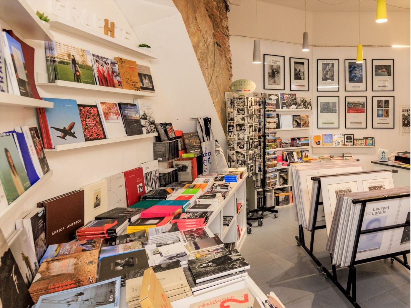 Présentation de la boutique avec livres, affiches et cartes postales en vente.